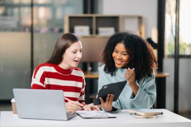 Ofiste dijital tablet kullanarak konuşan iki genç iş adamı.