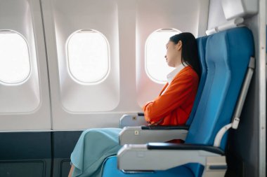 Genç Asyalı yönetici birinci sınıfta uçuyor, kadın uçakta uyuyor. 