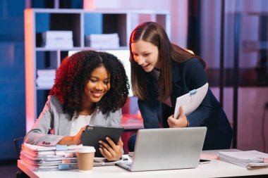 Kibar yönetici, iş çözümlerini paylaşıp tartışır ve modern ofiste, laptop, kahve ve tablet bilgisayarlı Afrikalı kadın pazarlama müdürüyle fikirler planlar.