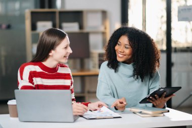 Ofiste dijital tablet kullanarak konuşan iki genç iş adamı.