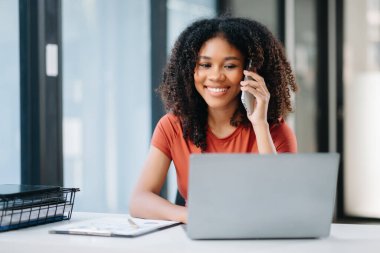 Diz üstü bilgisayar kullanan ve ofiste çalışırken akıllı telefondan konuşan bir girişimci. 