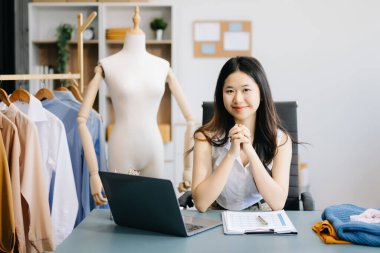  Moda tasarımcısının masasındaki Asyalı genç kadın stüdyoda çalışıyor.