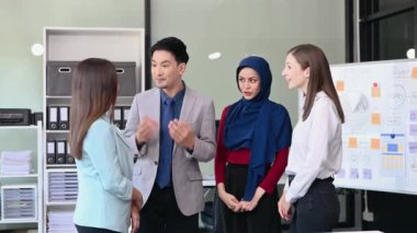 Bir grup genç Asyalı iş adamı yaratıcı ofiste modern girişimin iş planını tartışıyor ve el sıkışıyorlar. 