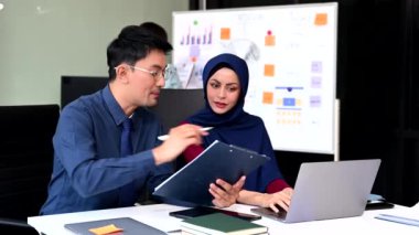 Genç Asyalı iş adamları dizüstü bilgisayar kullanarak yaratıcı ofiste modern girişimin iş planını tartışıyor. 