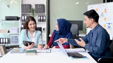 Bir grup genç Asyalı iş adamı bilgisayar ve dijital tablet kullanarak yaratıcı ofiste modern girişimin iş planını tartışıyor. 