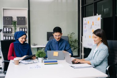 İş ortakları toplantıda belge ve fikirleri tartışıyor, yeni başlangıç projesiyle çalışıyorlar.