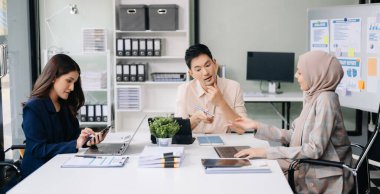 İş ortakları toplantıda belge ve fikirleri tartışıyor, yeni başlangıç projesiyle çalışıyorlar.