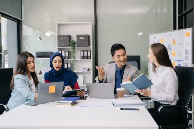 Çok ırklı genç yaratıcı insanlardan oluşan bir grup iş görüşmelerini tartışıyor fikir üreten tasarım projelerini ofisinde tartışıyor.