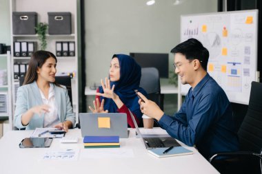 İş ortakları toplantıda belge ve fikirleri tartışıyor, yeni başlangıç projesiyle çalışıyorlar.