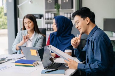 İş ortakları toplantıda belge ve fikirleri tartışıyor, yeni başlangıç projesiyle çalışıyorlar.