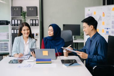 İş ortakları toplantıda belge ve fikirleri tartışıyor, yeni başlangıç projesiyle çalışıyorlar.