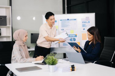 İş ortakları toplantıda belge ve fikirleri tartışıyor, yeni başlangıç projesiyle çalışıyorlar.