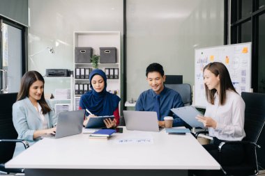 Çok ırklı genç yaratıcı insanlardan oluşan bir grup iş görüşmelerini tartışıyor fikir üreten tasarım projelerini ofisinde tartışıyor.