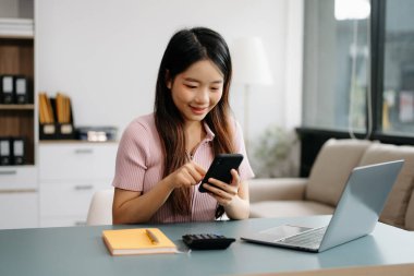 Ofiste çalışan iş kadınları, ofiste akıllı telefon ve dizüstü bilgisayar kullanıyorlar.