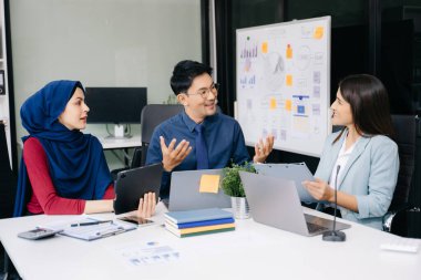 İş ortakları toplantıda belge ve fikirleri tartışıyor, yeni başlangıç projesiyle çalışıyorlar.