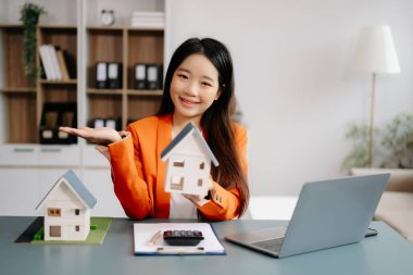 Emlak komisyoncusu ev modelini sunar. İş kadını, ofisteki ipotek kredisi teklifiyle ilgili müşteriye danışıyor 