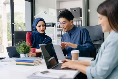 İş ortakları toplantıda belge ve fikirleri tartışıyor, yeni başlangıç projesiyle çalışıyorlar.