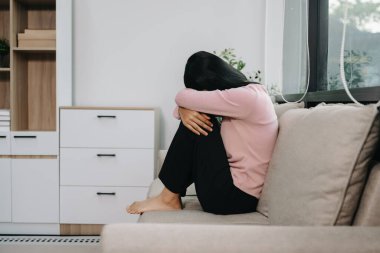 Evdeki kanepede oturan Asyalı kadın depresyonda. 