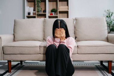 Asyalı kadın evdeki kanepede oturmuş depresyonda. 