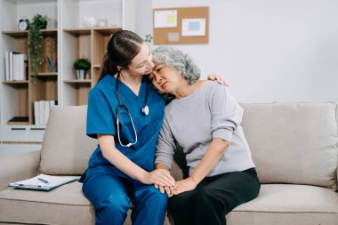 Genç hemşire yaşlı kadına yardım ediyor, el ele tutuşuyor, destek oluyor. Destekli yaşam tesisinde yaralanma üstüne tedavi ve rehabilitasyon