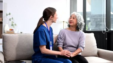  Genç bakıcı doktor yaşlı bir kadının elini tutuyor. Tıbbi servis kavramı.