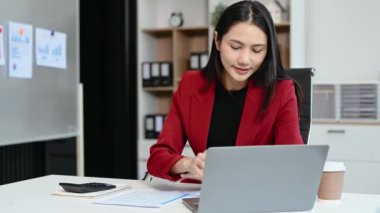 Ofiste belgelerle çalışan Asyalı iş kadını ve dizüstü bilgisayar. 