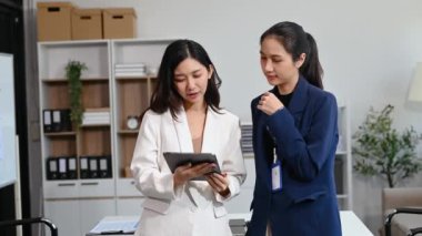 Modern ofiste dijital tablet kullanarak birlikte çalışan başarılı iş kadınlarının portresi