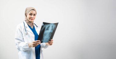 Müslüman bir Arap. Stüdyoda izole edilmiş beyaz arka planda röntgen çeken kadın doktor.
