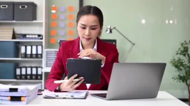 Ofiste dijital tablet ve dizüstü bilgisayar üzerinde çalışan Asyalı iş kadını 