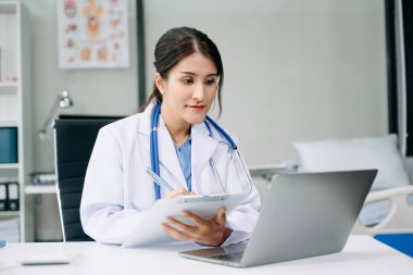Ofis hastanesindeki masada oturan güzel doktor. İş için dizüstü bilgisayar kullanan çekici bir kadın terapist. 