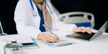 Tıbbi teknoloji konsepti. Modern ofiste dizüstü bilgisayar ve steteskopla çalışan bir doktor.