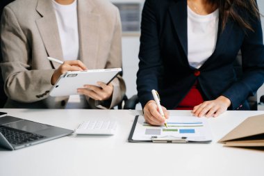Ofisteki yeni projeyi tartışan ve çalışan meslektaşlar dizüstü bilgisayar ve dijital tablet kullanıyorlar 