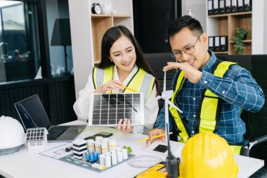 Asyalı iş adamları şirket ofisinde rüzgar enerjisi hakkında danışmanlık yapıyorlar. Mimari proje sitesinde ve model ev yapımında. Asya endüstrisi profesyonel 