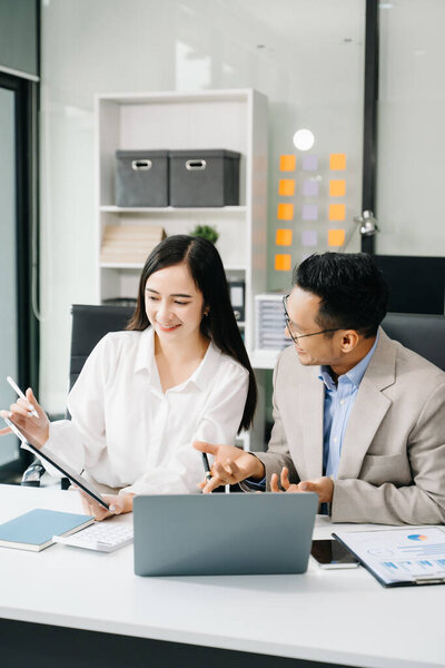 Two Asian business workers talking during meeting and using laptop at the office