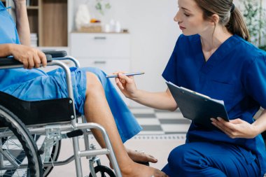 Hemşire evde yaşlı kadın hasta bacaklarına bakıyor. Tekerlekli sandalyede oturan yaşlı kadınla ilgilenen terapist. Tıbbi servis kavramı