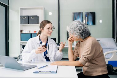 Genç doktor, hastanedeki yaşlı kadın hastaya nasıl ilaç kullanılacağını açıklar. 