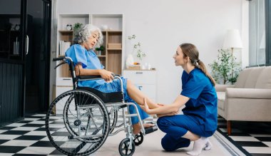 Hemşire evde yaşlı kadın hasta bacaklarına bakıyor. Tekerlekli sandalyede oturan yaşlı kadınla ilgilenen terapist. Tıbbi servis kavramı