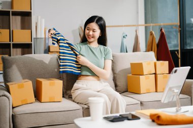 Başlangıçta küçük işletme KOBİ 'si, dijital tablet kullanan girişimci kadın, ürün kutularının hazırlanması için çevrimiçi alışveriş siparişi alıp kontrol ediyor 