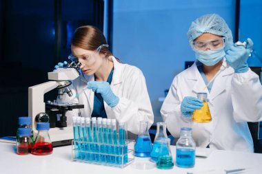 Tıp laboratuarında araştırma yapan genç bilim adamları. Tıp laboratuarında mikroskop kullanan araştırmacılar..  