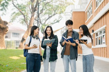 Üniversite öğrencileri sabahları kampüs parkında çalışıyor. Dijital tablet ve akıllı telefonla çalışıyorlar.