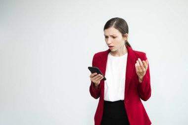 Hayal kırıklığına uğramış iş kadını beyaz arka planda duruyor ve akıllı telefon kullanıyor.