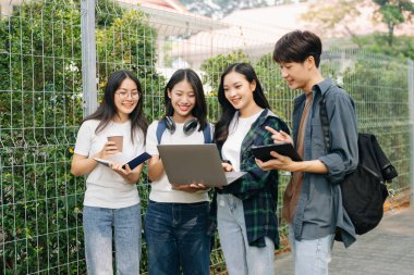 Üniversite öğrencileri sabahları kampüs parkında dijital tablet ve dizüstü bilgisayarla çalışıyorlar. 