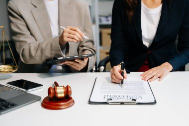 İş adamları ve avukatlar masada dizüstü bilgisayar ve tabletle kontrat belgelerini tartışıyor. Hukuk kavramları, tavsiyeler, hukuk hizmetleri. 