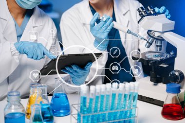 Laboratuvarda çalışan bilim adamları dijital tablet ve test örnekleri kullanıyorlar. 