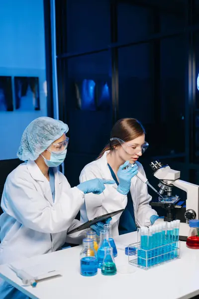 stock image Young scientists conducting research investigations in a medical laboratory, a researchers using a microscope and digital tablet in laboratory for medicine.  
