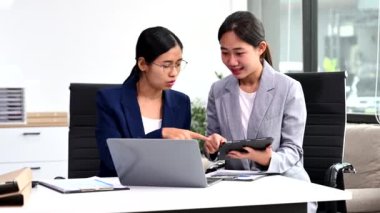 Modern ofiste birlikte çalışan başarılı iş kadınlarının portresi, dizüstü bilgisayar ve dijital tablet kullanarak 