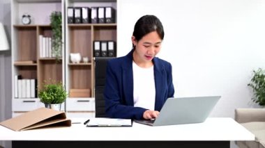 Ofiste belgelerle çalışan Asyalı iş kadını ve dizüstü bilgisayar. 