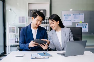 Nazik yönetici yönetici iş çözümlerini modern ofiste dizüstü bilgisayar ve tablet kullanarak paylaşır ve tartışır.