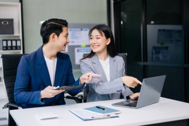 Nazik yönetici yönetici iş çözümlerini modern ofiste dizüstü bilgisayar ve tablet kullanarak paylaşır ve tartışır.