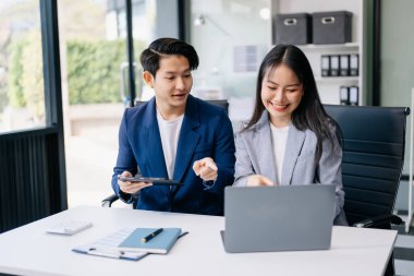 Nazik yönetici yönetici iş çözümlerini modern ofiste dizüstü bilgisayar ve tablet kullanarak paylaşır ve tartışır.